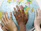 Hände von unterschiedlichen Menschen halten gemeinsam einen Globus.