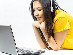 Junge Frau am Laptop mit Kopfhörer