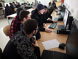Schüler und Schülerinnen vor ihrem gemeinsamen Computer im Klassenzimmer.