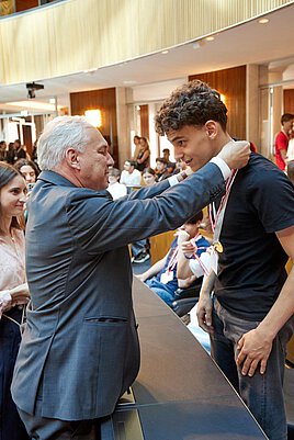 Nationalratspräsident Walter Rosenkranz hängt einem jungen Burschen eine Medaille um