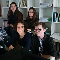 Schüler und Schülerinnen vor ihrem gemeinsamen Computer.