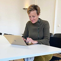 Sibylle Hamann sitzt auf einem Tisch vor ihrem Laptop