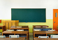 Schulbänke vor einer Tafel in einer leeren Schulklasse