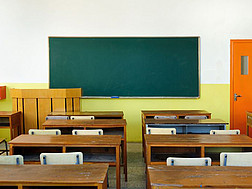 Das Bild zeigt ein leeres Klassenzimmer mit Blick auf die grüne Tafej