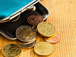 Eine türkise Geldbörse, aus der ein paar Münzen herausrutschen