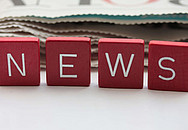 Scrabble Steine, die das Wort News darstellen, dahinter liegt eine Zeitung.