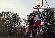 Zwei Frauen springen während eines Basketballspiels zum Korb hoch