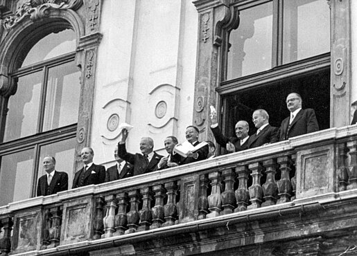 „Österreich ist frei!“ Leopold Figl zeigt den jubelnden Menschen vom Balkon des Schlosses Belvedere den unterzeichneten Staatsvertrag. © Historisches Archiv ORF / Fritz Kern