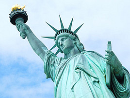 Ansicht der Freiheitsstatue in New York von schräg unten vor einem teilweise bewölkten Himmel