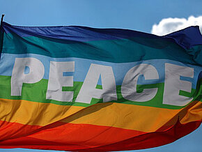 Fahne in Regenbogenfarben mit Aufschrift "Peace"