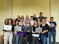 Gruppenfoto der Schulkasse mit ihren Laptops in den Händen