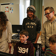 Schülerinnen und Schüler vor ihrem gemeinsamen Computer.
