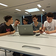 4 Schüler vor ihrem gemeinsamen Laptop im Klassenzimmer