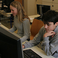 Schülerin und Schüler vor ihren Computern.