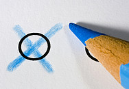 Blaues Kreuz auf einem Stimmzettel, daneben liegt ein blauer Buntstift.