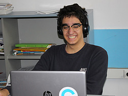 Ein Schüler lacht, während er hinter seinem Laptop sitzt