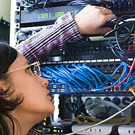 Eine Elektrotechnikerin prüft die Kabel eines Schaltkastens 