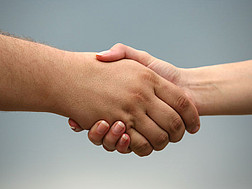 Detailansicht von einem Handschlag von zwei Menschen vor einem grauen Hintergrund