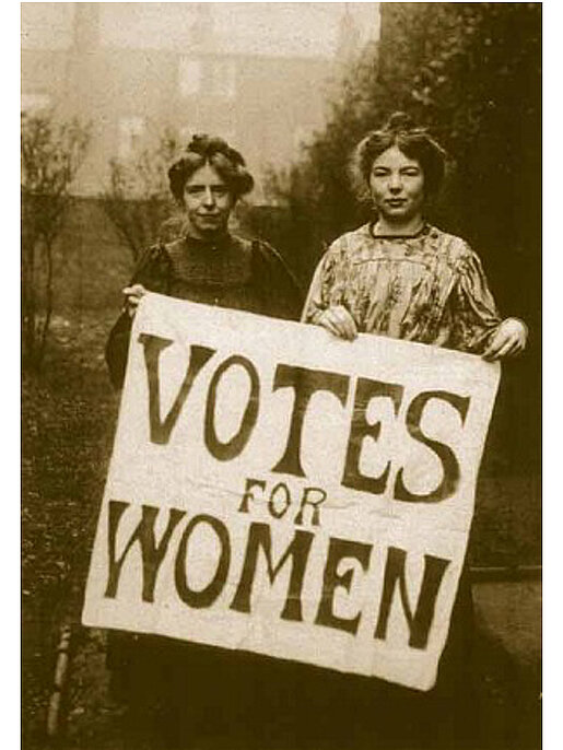 Historisches Bild zeigt zwei Frauen, die ein Plakat mit der Aufschrift votes for women steht.