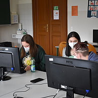 Drei SchülerInnen sitzen vor einem Computer und unterhalten sich 
