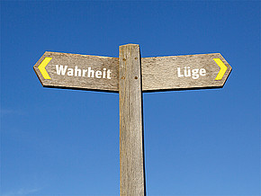 Ein Wegschild mit den beiden Schildern "Wahrheit" und "Lüge", die jeweils in verschiedene Richtungen weisen 