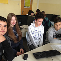 Schüler und Schülerinnen vor ihrem gemeinsamen Laptop.
