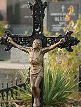 Ein metallenes Kreuz mit einer Jesus-Figur auf einem Friedhof