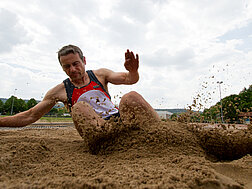 Ein Weitspringer landet im Sand.