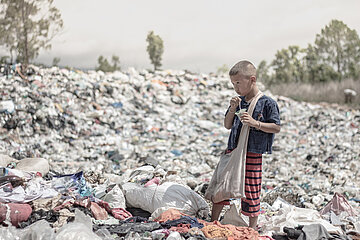 Kleiner Junge sammelt besonderen Müll auf einer Müllhalde