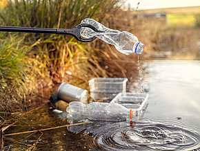 Plastikflasche wird aus Fluss gezogen