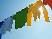 Bunte Kleidungsstücke, die auf einer Wäscheleine unter dem blauen Himmel in der Sonne zum Trocknen hängen