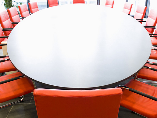 Großer Sitzungsraum mit roten Stühlen und ovalem Tisch