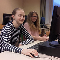 Zwei lachende Schülerinnen vor ihrem gemeinsamen Computer.