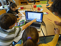 Drei Kinder sitzen vor einem Bildschirm bei einem Online-Workshop