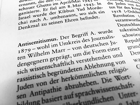 Ein aufgeschlagenes Wörterbuch mit der Definition von Antisemitismus.