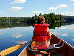 Ein junges Mädchen rudert in einem Kanu auf einem See.