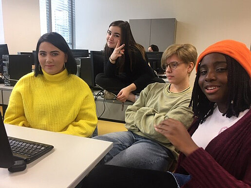 Schüler und Schülerinnen vor ihrem gemeinsamen Computer.