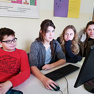 Schüler und Schülerinnen vor ihrem gemeinsamen Computer.