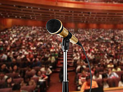 Ein Mikrophon mit Mikrophonständer vor einem großen Publikum in einem Saal