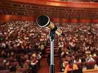 Ein Mikrophon ist in einem Seminarraum vor einem großen Publikum aufgestellt.