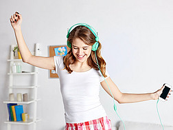Junge Frau tanzt mit Kopfhörern auf dem Kopf