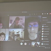 SchülerInnen aus dem distance learning auf einer großen Videoleinwand 