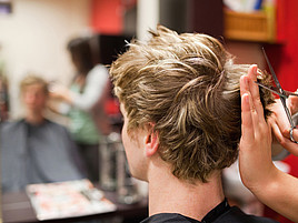 Eine Friseurin schneidet einem Kunden die Haare.