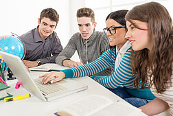 Vier junge Menschen sitzen vor einem Computer