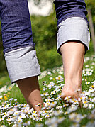 Jemand geht barfuß über eine Blumenwiese.