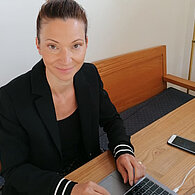 Susanne Fürstl sitzt auf einer Bank vor einem Laptop
