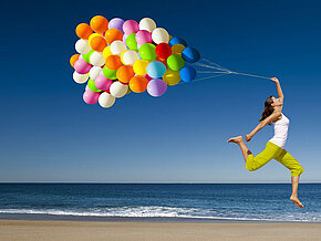 Mädchen mit bunten Luftballons vor blauem Himmel