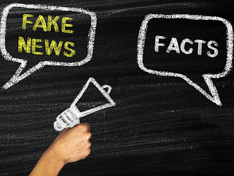 Zwei Sprechblasen mit den Wörtern "Fake News" und "Facts" und ein Megaphon auf schwarzem Hintergrund 