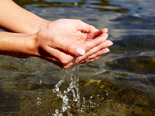 Hände schöpfen reines Flußwasser