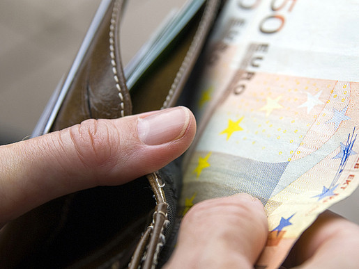 Jemand nimmt 50-Euro-Scheine aus einem Portemonnaie.